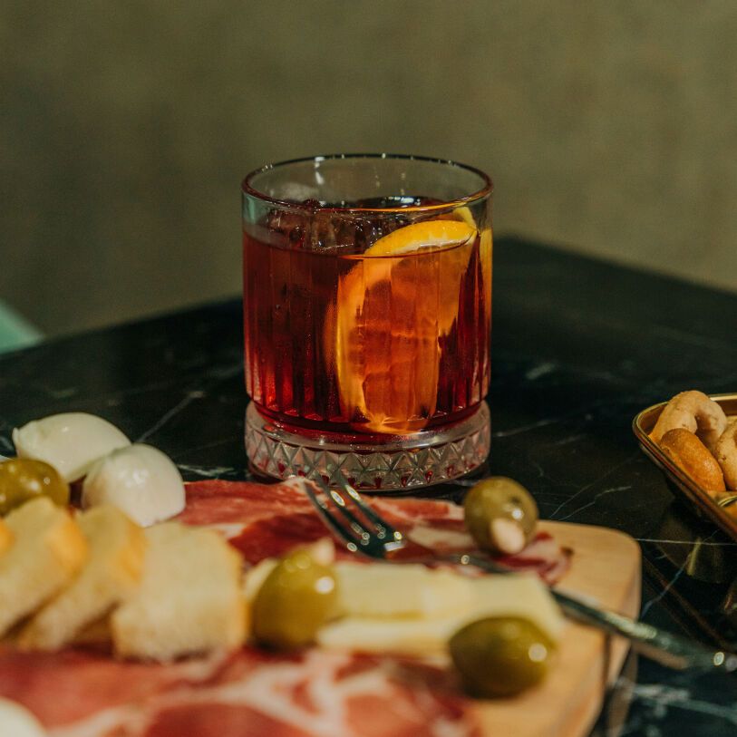 En charkbricka och Negroni som är typiskt för en Aperitivo